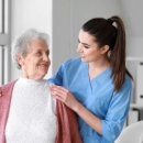 Caregiver assisting elderly woman indoors
