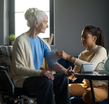 Caregiver measuring blood pressure of senior woman