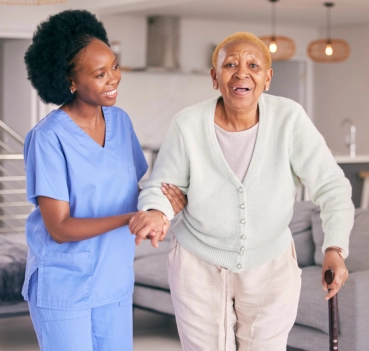Caregiver assisting senior woman walking indoors