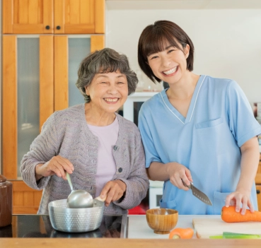Caregiver helping senior woman cook in kitchen
