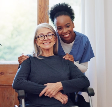 Caregiver smiling behind senior woman in wheelchair
