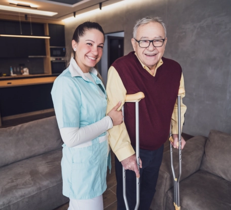 Caregiver assisting smiling senior man with crutches